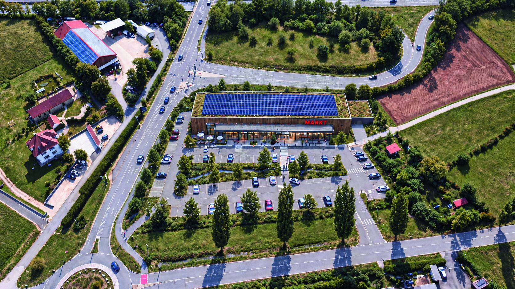 AI-Visualisierung des geplanten Marktes mit Parkplatz und Grünflächen am Kreisverkehr